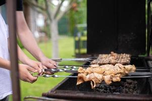 Hände halten Spieße mit Fleisch auf das Magnale foto