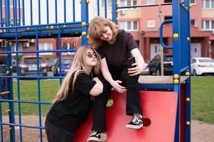 zwei Teenager Mädchen sind Sitzung auf das Spielplatz mit Telefone nehmen Selfies foto