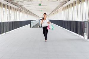 Porträt einer glücklich lächelnden Frau mit Einkaufstüten im Korridorweg. schöne Frau mit einer Papiertüte. foto