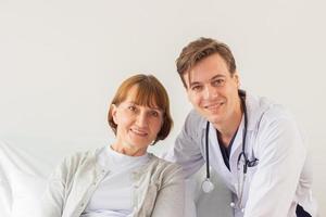 das Arzt ist Prüfung das geduldig im das Krankenhaus. kaukasisch Arzt tragen Kleid und Hören Gerät und ein weiblich geduldig suchen beim das Kamera beim das Krankenhaus foto