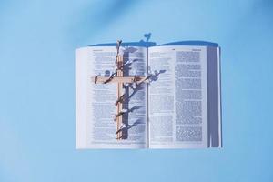 Kreuz dekoriert Blumen mit öffnen heilig Bibel auf Blau Hintergrund. Ostern Urlaub minimalistisch Konzept foto