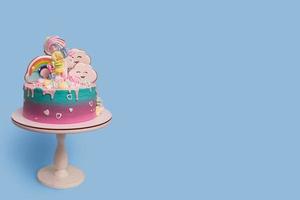 schön festlich mit Einhorn Kinder- Kuchen auf ein Stand auf ein Blau Hintergrund mit Kopieren Raum foto