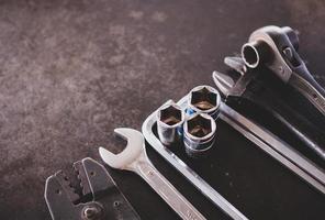 Hand Werkzeuge bestehend aus von Schraubenschlüssel, Zange, Steckdose Schraubenschlüssel, gelegt aus auf alt Stahl Teller Hintergrund. foto