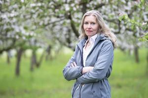 Porträt von ein schön mittleren Alters Frau im ein Blühen Garten. foto