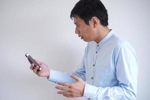 das Bild von ein asiatisch Mann suchen erschrocken beim Sehen ein Botschaft auf seine Handy, Mobiltelefon Telefon oder lesen erschreckend Nachrichten foto