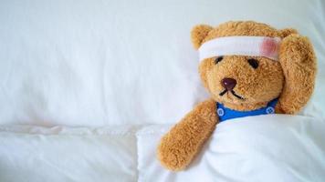 das Teddy Bär war krank im Bett nach Sein verletzt im ein Unfall. bekommen Leben Versicherung und Unfall Versicherung Konzept foto