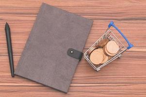 Notizbuch auf dem Schreibtisch mit Münzen in einem winzigen Wagen foto