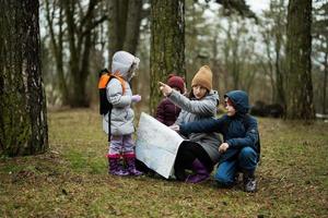 Mutter und Kinder mit Karte im das Wald. foto