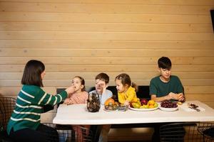 Mutter mit vier Kinder Essen Früchte im hölzern Land Haus auf Wochenende. foto