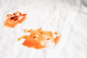 schmutziger tomatensaucenfleck oder ketchup auf tuch zum waschen mit waschpulver, reinigungskonzept für die hausarbeit. foto