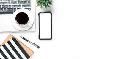 Büro Schreibtisch mit Laptop Computer, leer Bildschirm Clever Telefon, Tasse von Kaffee, Stift, Notizbuch auf Weiß Hintergrund, oben Aussicht mit Kopieren Raum, spotten hoch. foto