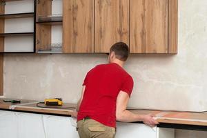 Handwerker, Möbel Hersteller und Monteur, installiert ein modern Küche im das Haus mit Werkzeuge im Hand. Benutzerdefiniert Möbel Konzept, Zuhause Verbesserung, Renovierung foto