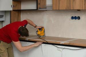Handwerker, Möbel Hersteller und Monteur, installiert ein modern Küche im das Haus mit Werkzeuge im Hand. Benutzerdefiniert Möbel Konzept, Zuhause Verbesserung, Renovierung foto