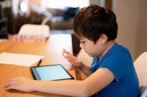 Bildung Konzept, Schule Kind Lernen online Klasse Zimmer beim heim, Kind mit Tablette zum Hausaufgaben, jung Junge studieren online Video Forderung, E-Learning oder Zuhause Schule, Kind Lernen mit Neu Technologie foto