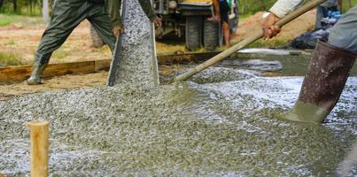 bauarbeiter gießen nassen beton auf der baustelle. Bauarbeiter, der mit Transportbeton arbeitet, der aus einem Zementmischwagen gegossen wird. Konzept des Bauunternehmers. Baumeister Zement gießen. foto