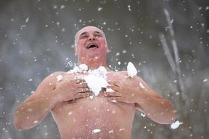 ein Erwachsene Mann ist gehärtet durch Schnee auf ein Winter Tag. Mann mit Schnee Duschen zu härten seine Körper foto