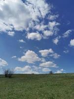 Blau Frühling Himmel hinter ein Grün Hügel foto