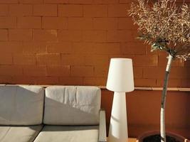 Weiß Sofa, Lampe und Baum gegen ein Terrakotta Mauer foto