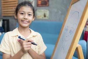 wenig Mädchen Schreiben auf leeren Whiteboard mit ein Marker Stift foto