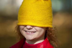 das wenig Mädchen gezogen ein Gelb gestrickt Hut Über ihr Augen. fallen hat kommen. foto