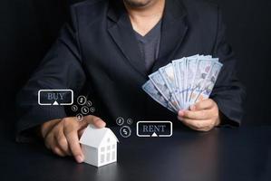 Geschäftsmann halt Papier Haus und Dollar Banknote auf schwarz Hintergrund foto