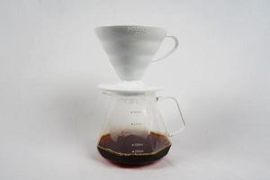 brauen Kaffee im ein Trichter. das hario v60 Kaffee Trichter ist auf das Server. . das Prozess von brauen das Kaffee Spezialität. isoliert auf Weiß Hintergrund foto