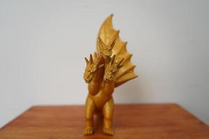 golden Drachen Ghidorah isoliert auf Weiß Hintergrund. auf hölzern Tabelle foto