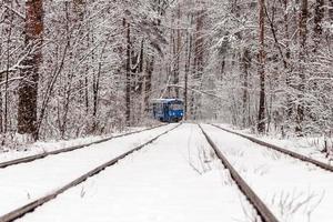 eine alte Straßenbahn, die sich durch einen Winterwald bewegt foto