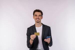 Porträt von glücklich jung Geschäftsmann Stehen mit Handy, Mobiltelefon Zelle Telefon und halten Anerkennung Bank Karte isoliert auf Weiß Farbe Hintergrund Studio foto