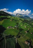 schweizerisch Wiese Felder mit Häuser und Berge, im wolkig Wetter foto