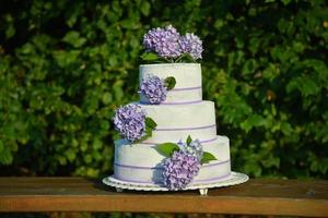 ein Foto einer Hochzeitstorte mit violetten Blütenhortensien