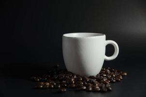 Weiß Tasse mit Kaffee Bohnen im dunkel Licht foto