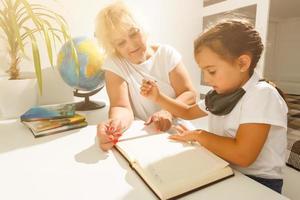 Babysitter und wenig Mädchen tun Hausaufgaben foto