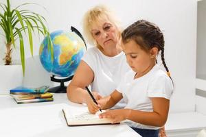 Oma Hilfe Enkelin tun Schule Hausaufgaben zusammen beim Zuhause foto