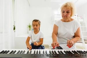 ein Mädchen mit Oma spielen das Klavier. foto