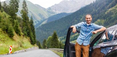 reisen, Tourismus, Straße Reise, Transport und Menschen Konzept - - glücklich Mann in der Nähe von Auto Über Berge Hintergrund foto