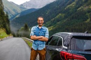 reisen, Tourismus, Straße Reise, Transport und Menschen Konzept - - glücklich Mann in der Nähe von Auto Über Berge Hintergrund foto