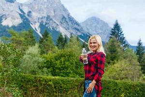Abenteuer jung Asien Frau Trekking und Trinken Wasser von ein Flasche im das Berge, Sommer- Reise Konzept foto