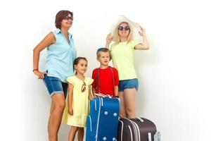 Familie Reise - - zwei Frauen mit Junge und Mädchen Stand in der Nähe von Koffer. isoliert, Weiß Hintergrund foto