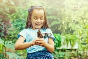 wenig Mädchen ist spielen mit Schmetterling im Natur foto