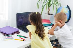 covid-19 Coronavirus und Lernen von heim, Zuhause Schule Kind Konzept. wenig Kinder Studie online Lernen von Zuhause mit Laptop. Quarantäne und Sozial Distanzierung Konzept. foto