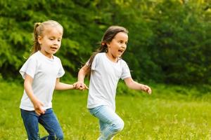 zwei wenig Schwestern Lauf auf das Straße im Park auf ein sonnig Sommer- Tag. Familie Zeit. süß Babys. Sanft Fokus foto