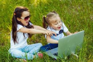 zwei Kinder spielen Laptop oder Notizbuch im das Garten zum Bildung. süß Mädchen Aufpassen Karikatur auf pc screen.the Konzept ist Clever Lernen von Internet und Sozial Medien foto