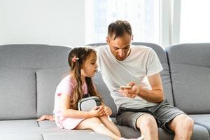 amerikanisch Vater und Tochter mit virtuell Wirklichkeit Brille und lächelnd im Leben Zimmer foto