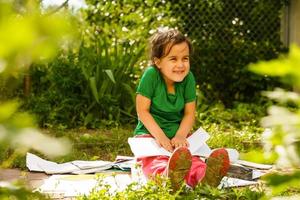 süß wenig blond Mädchen lesen Buch draußen auf Gras foto