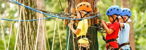 Kinder - - ein Junge und ein Mädchen im das Seil Park bestehen Hindernis. Bruder und Schwester steigen das Seil Straße foto