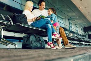 Familie im Flughafen. attraktiv jung Frau, gut aussehend Mann und ihr süß wenig Tochter sind bereit zum Reisen glücklich Familie Konzept. foto