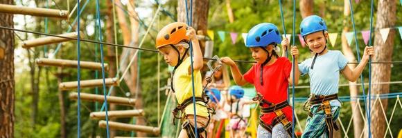 Kinder - - ein Junge und ein Mädchen im das Seil Park bestehen Hindernis. Bruder und Schwester steigen das Seil Straße foto