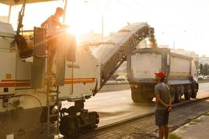 schön Sonnenuntergang über das Straße Walze Arbeiten auf das Neu Straße Konstruktion Seite? ˅ foto