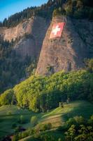 das schweizerisch Flagge platziert auf ein steil Berg foto